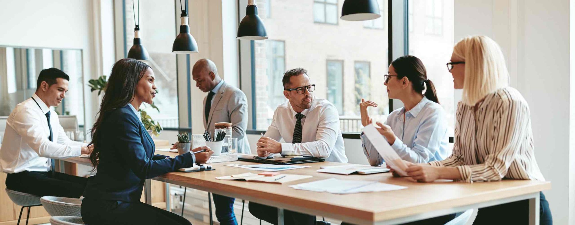 A group of businessmen and women discussing cybersecurity around a desk.
