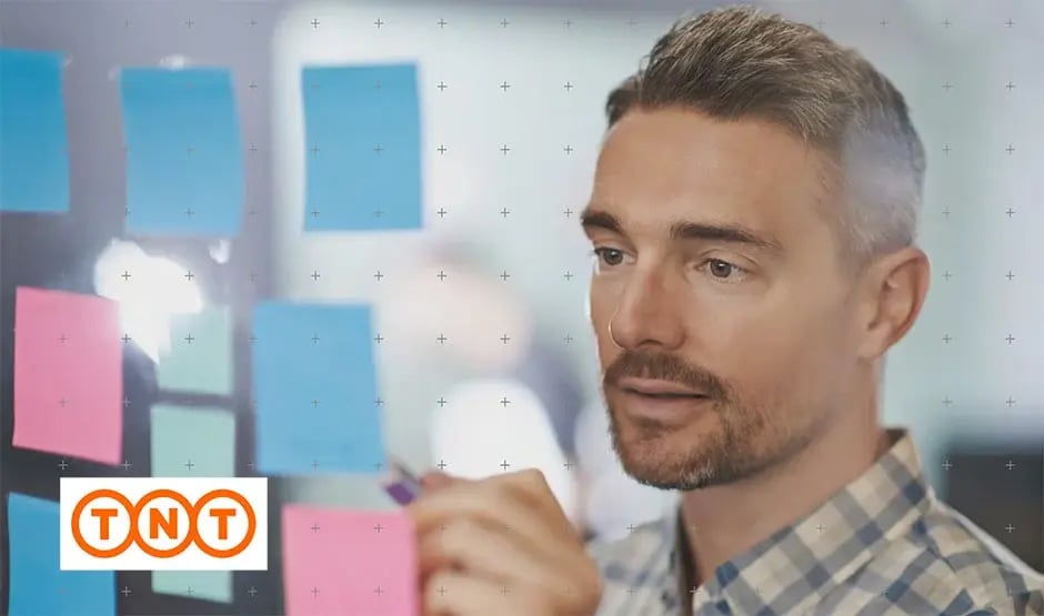 Man writing on a post it note that is stuck on a window